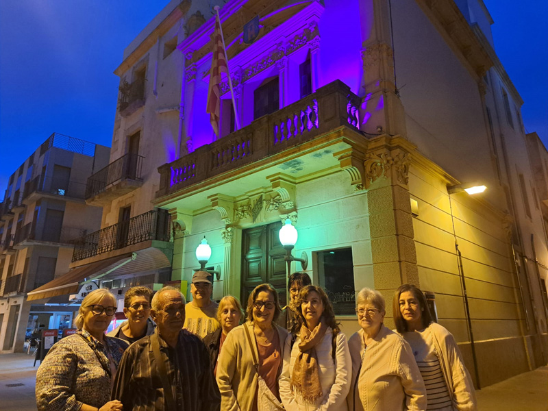 Persones afectades per aquestes malalties davant la façana il·luminada de l'Ajuntament. (Foto: Ajuntament de Palamós).