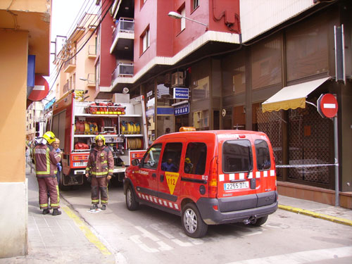 Els bombers davant del quadre incendiat, situat a la part superior de la imatge, a la façana de color granat.