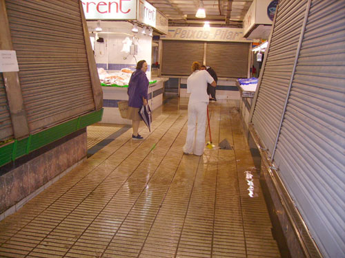Una treballadora del mercat municipal cobert, retirant aigua.