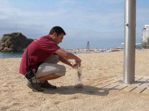 Un tècnic recull una mostra de sorra d'una dutxa de platja.