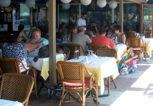 Turistes en una terrassa del passeig del Mar de Palamós.