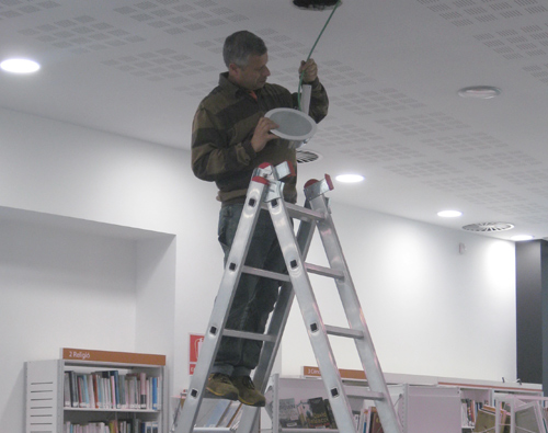 Un operari de la brigada municipal substituïnt els llums de la biblioteca.
