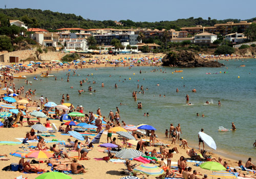Imatge de la platja de la Fosca plena, a l'estiu.