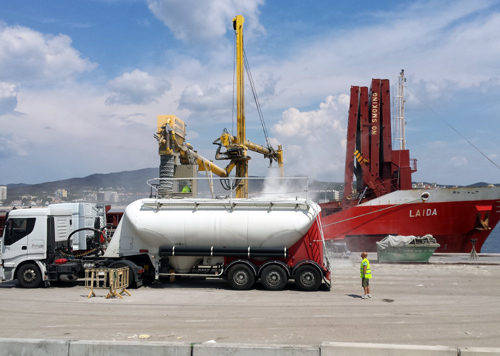 Un vaixell transfereix la seva càrrega en un camió en el port de Palamós.