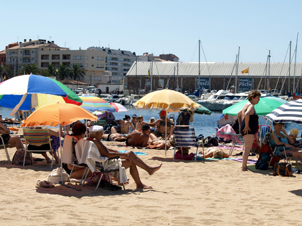 Banyistes protegint-se del sol a la platja Gran de Palamós.