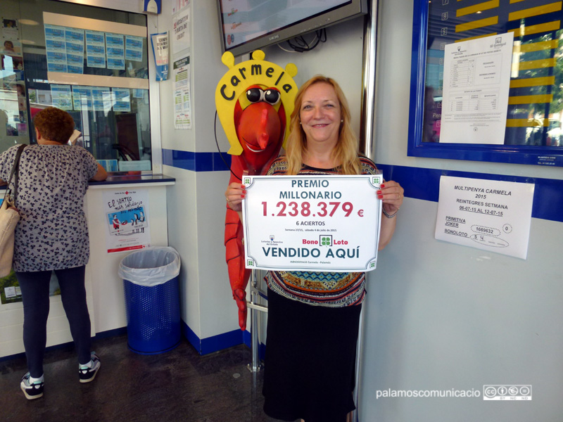 Maria Àngels Vallès, treballadora de l'administració Carmela, amb el cartell del premi de la Bonoloto.