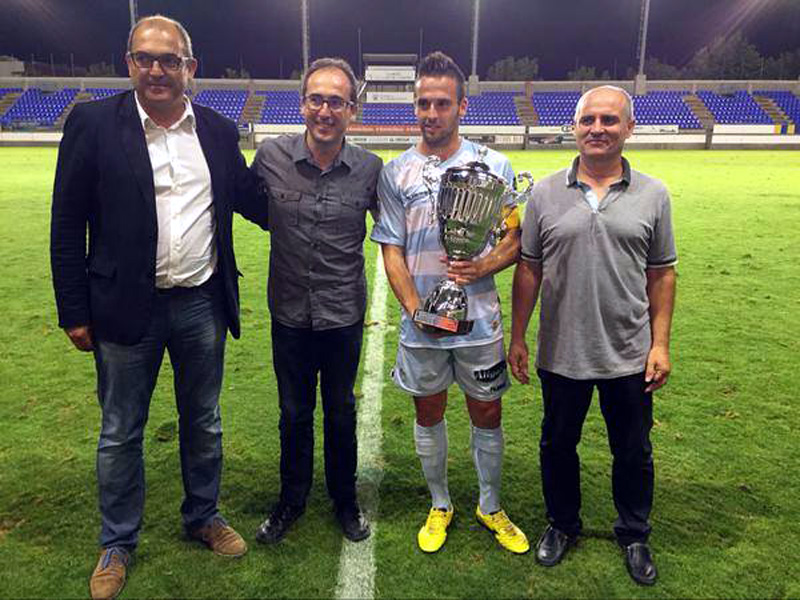 El capità del Llagostera, acompanyat de les autoritats, amb el trofeu Vila de Palamós. (Foto: Palamós CF).