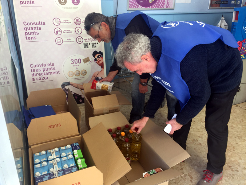 Dos dels voluntaris del Gran Recapte d'Aliments recollint els primers productes, aquesta tarda.
