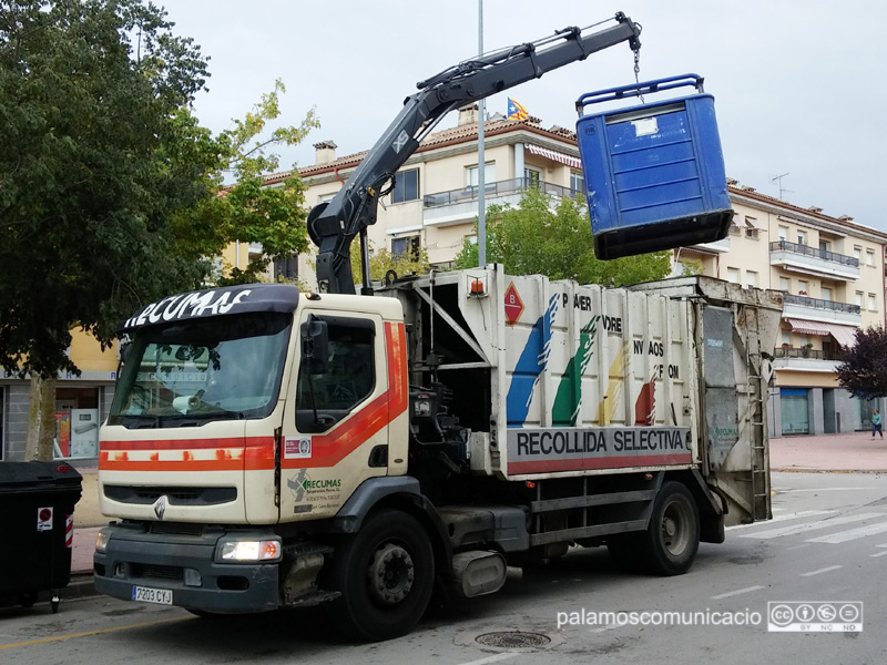 Un camió recollint els residus d'un contenidor de cartró i paper.