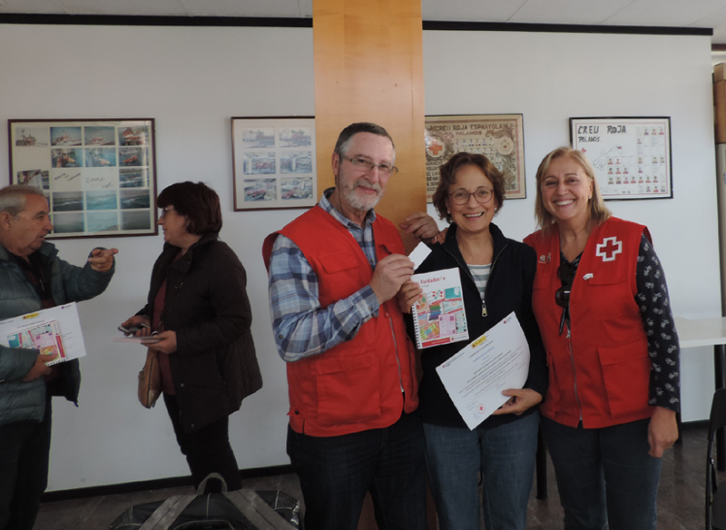 Una participant en el curs rep una guia de consells per a cuidadors per part del voluntariat de Creu Roja. (Foto: Creu Roja Palamós).