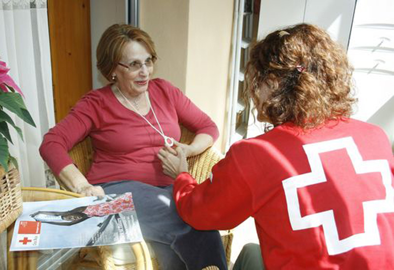 Una voluntària de Creu Roja col·loca un dispositiu d'assistència a una usuària del servei. (Foto: Creu Roja)