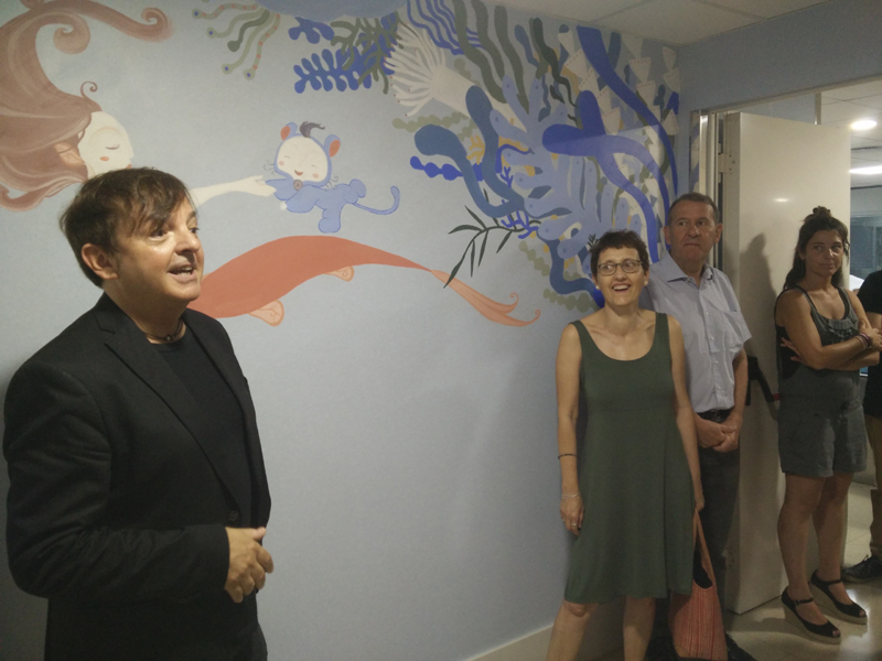 L'il·lustrador Ignasi Blanch, a l'esquerra, davant un dels murals de pediatria de l'hospital. (Foto: SSIBE).