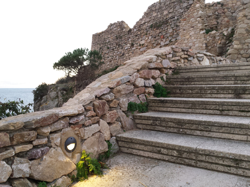 imatge d'una de les balises ubicades al camí de ronda, amb el castell de Sant Esteve al fons. (Foto: Ajuntament de Palamós).