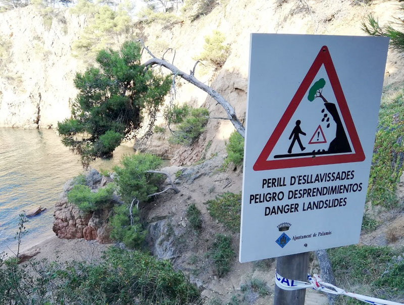 Un rètol que avisa del risc de despreniments a la cala dels Corbs. (Foto: Ajuntament de Palamós).