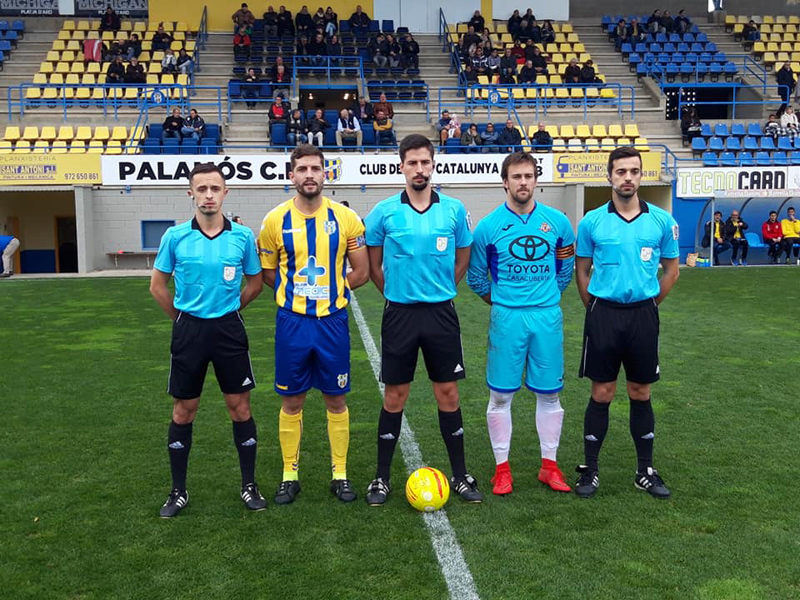 El capità David Cano, amb el seu homòleg del Vic i la tripleta arbitral, ahir abans del partit de diumenge. (Foto: Palamós CF).