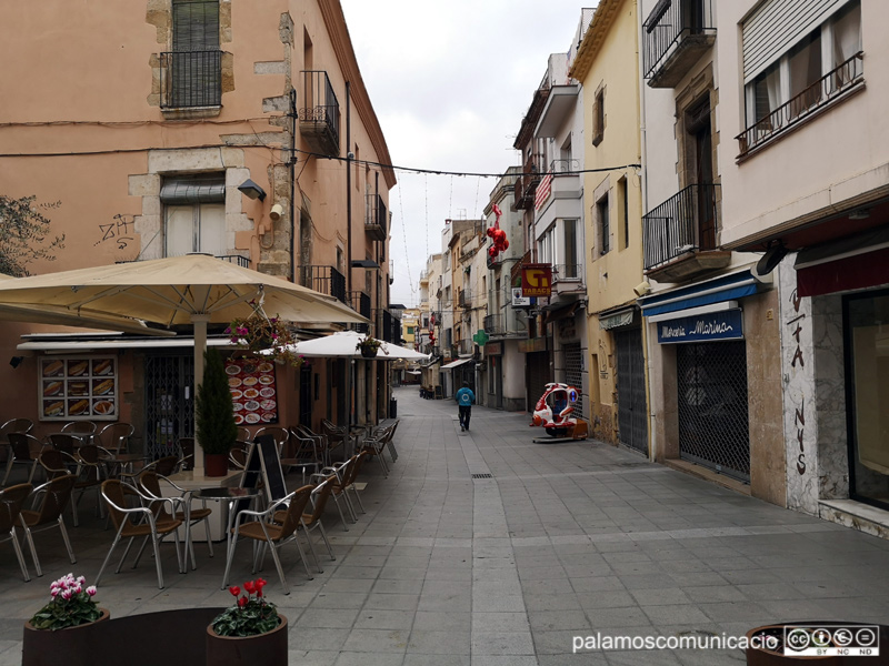 La majoria de comerços tancats en un carrer Major buit, un diumenge al matí.