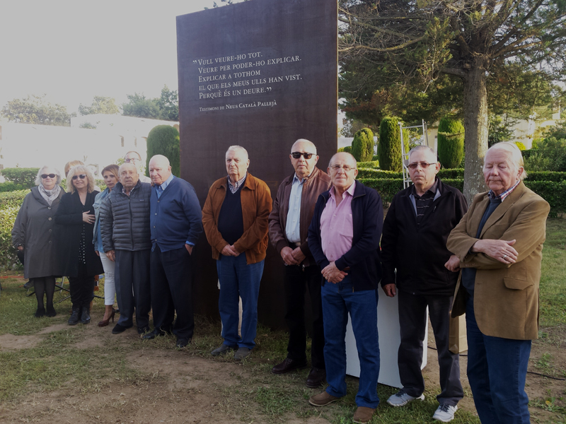 Familiars dels nou veïns del municipi que varen ser deportats, davant l'escultura dedicada a la seva memòria, al cementiri de Sant Joan. (Foto: Ajunta