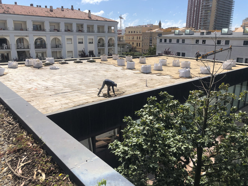 Operaris de la brigada treballant damunt la coberta de la Biblioteca Municipal. (Foto: Ajuntament de Palamós).