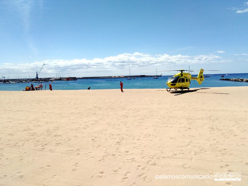L'helicòpter del SEM i, a l'esquerra, els sanitaris atenent la víctima, avui a la platja Gran.