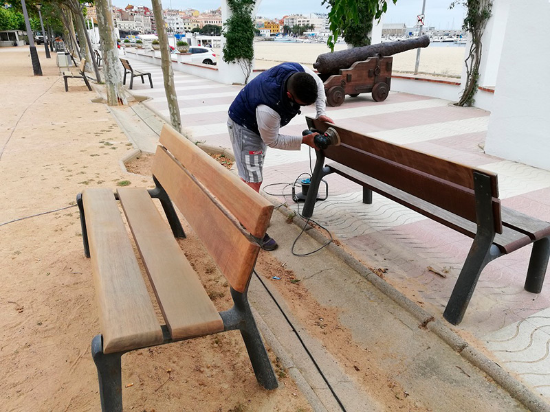 Un operari realitzant les feines de polit dels bancs del passeig. (Foto: Ajuntament de Palamós).