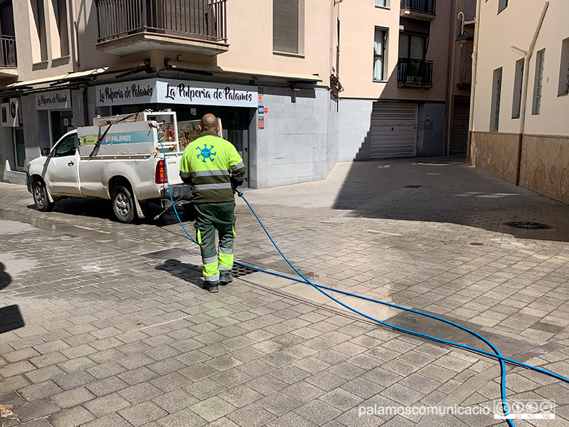 Un operari d'Urbaser neteja amb aigua a pressió el carrer Nou.