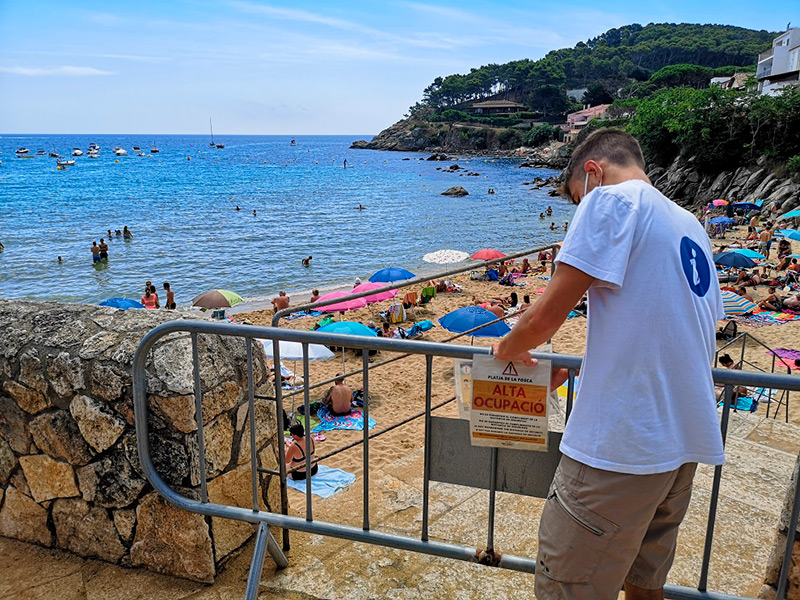 Un informador col·loca una tanca advertint de l'alta ocupació de la Fosca, aquest passat divendres. (Foto: Ajuntament de Palamós).