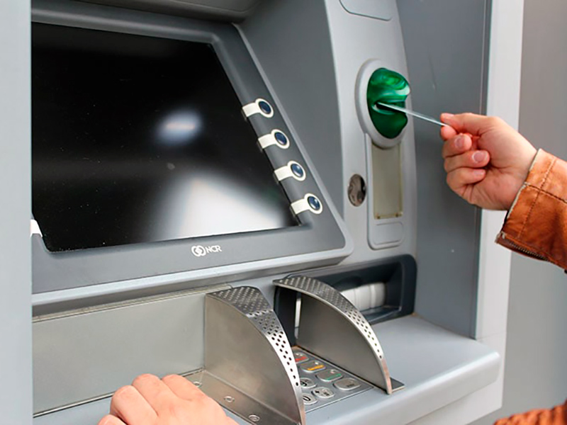 Una persona treu diners d'un caixer automàtic.