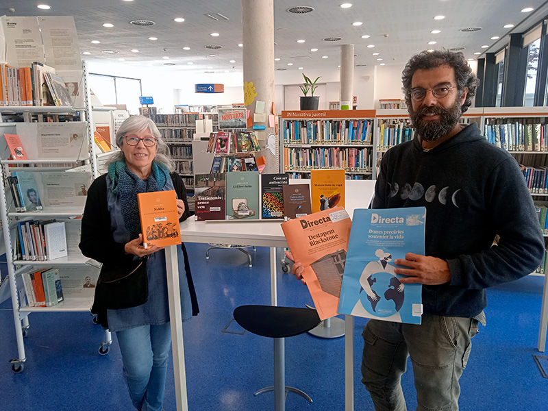 Roser Huete i Alexan Weltz fent entrega de la donació de llibres en nom de la CUP Palamós - Vila-romà. (Foto: CUP Palamós Vila-romà).
