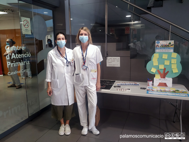 Les infermeres Laia Esteve i Ana Maria Cortada al costat de la taula informativa que hi ha al vestíbol del CAP.
