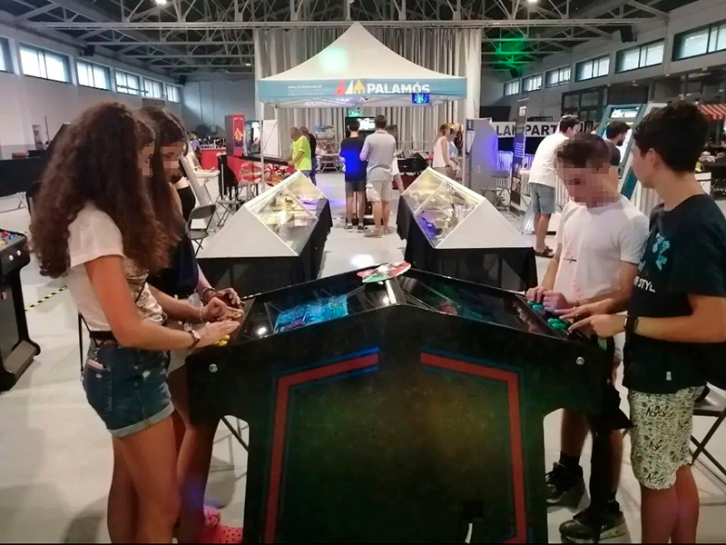 Quatre joves jugant amb una màquina recreativa retro. (Foto: Punt Jove Palamós).