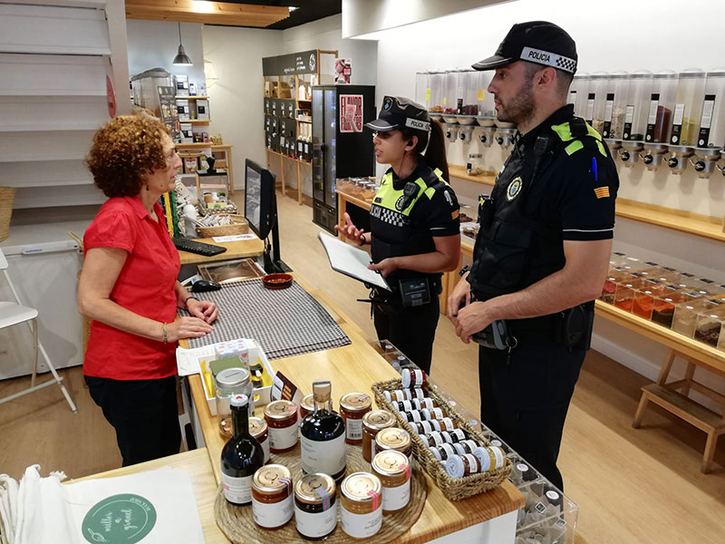 Dos agents de la Policia Local de Palamós fent una tasca informativa en un comerç del carrer Major. (Foto: Ajuntament de Palamós).