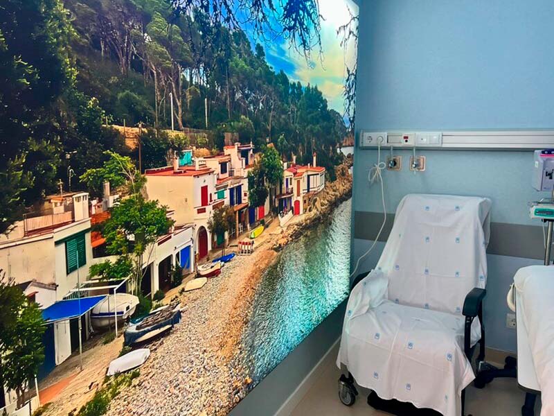 imatge d'un box d'hospital de dia mèdic amb una fotografia retroil·luminada de s'Alguer en una de les parets. (Foto: SSIBE).