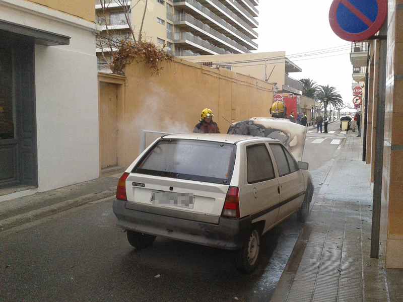 Bombers apagant el foc en el cotxe, aquest matí.